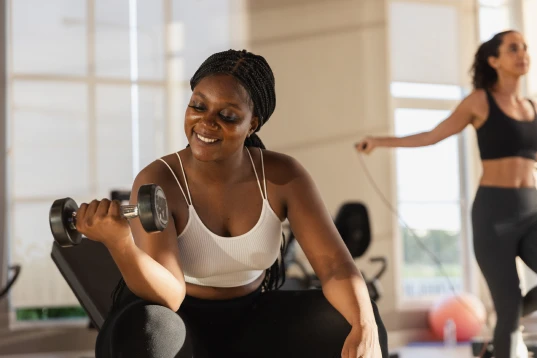 Total Fit - Academias e Treinos On-line Um homem e uma mulher na academia, realizando agachamento afundo e alguns equipamentos do fundo da imagem. #ParaTodosVerem
